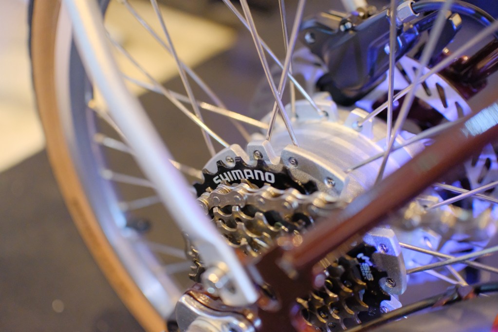 Close-up of a e-bike's rear wheel showcasing the Shimano gear system, featuring spokes and a motor hub with a modern, sleek design. The ban on e-bikes.