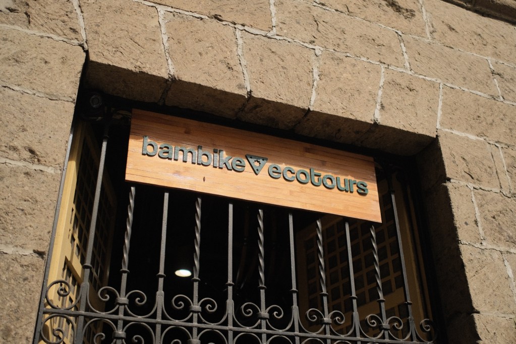 Sign for 'bambike ecotours' displayed on a stone wall with wrought iron bars.